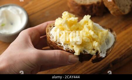 Toast with scrambled egg. Hand holding toast with cream cheese and scrambled egg Stock Photo