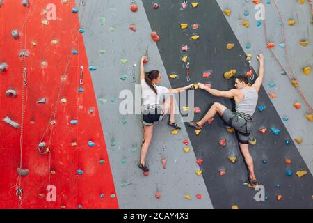 Friends spending their time at climbing wall. rare view photo. Stock Photo