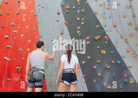 personal trainer talking with a pretty girl and pointing at the wall in the sport center. rare view. guy giving advice to a girl Stock Photo