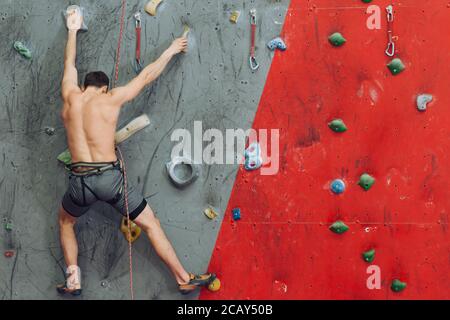 young man having some problems while climbing at gym. rare view. copy space Stock Photo