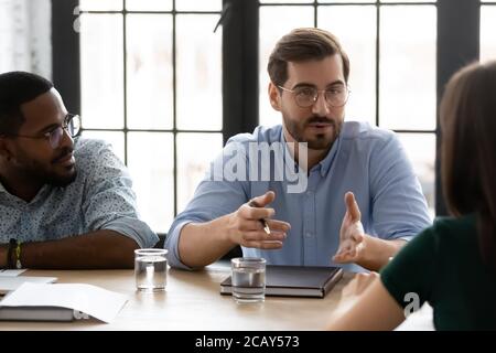 Confident young businessman wearing glasses speaking at corporate meeting Stock Photo