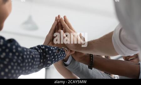 Close up diverse colleagues joining hands, giving high five Stock Photo