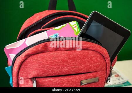 Preparing for school. A notebook, a pack of colored pencils and a tablet can be seen from the open school bag. The need now at school - gadgets Stock Photo
