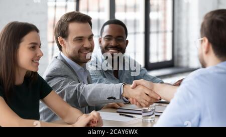 Smiling business people shaking hands, sitting at table in boardroom Stock Photo