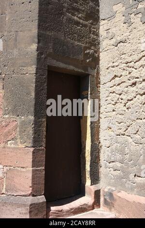 Old heavy square, wooden, massive door in stone wall to enter St. Martin's Church in Gothic architectural style in French town Colmar. Stock Photo