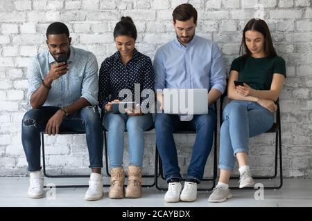 Diverse candidates waiting for job interview, using mobile devices Stock Photo
