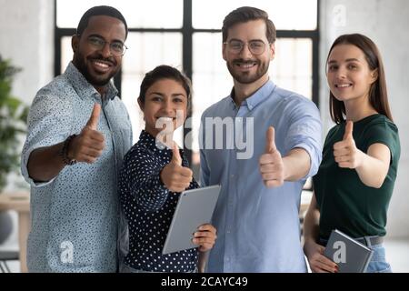 Smiling diverse employees team showing thumbs up at camera Stock Photo