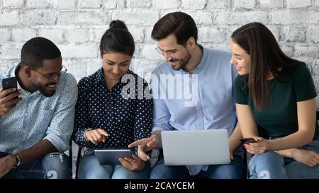 Friendly diverse candidates talking, using mobile devices, waiting for interview Stock Photo