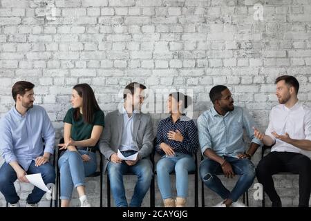 Young diverse candidates chatting, talking while waiting for job interview Stock Photo
