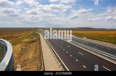 highway in steppe against a blue sky,long road stretching out into the distance. Stock Photo