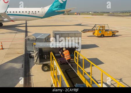 Verona, Italy - September 2018: Airport worker using a conveyor belt to load luggage into an aircraft Stock Photo