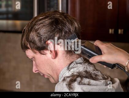 Close up of caucasian man having his hair cut at home during quarantine for coronavirus. Using electric clipper Stock Photo