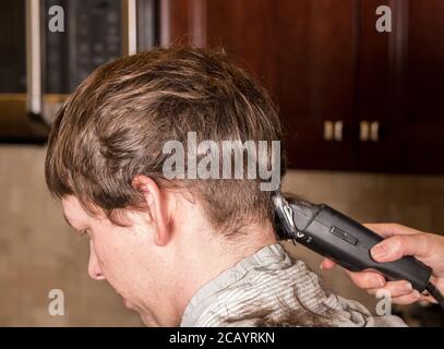 Close up of caucasian man having his hair cut at home during quarantine for coronavirus. Using electric clipper Stock Photo