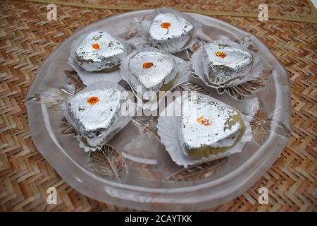Indian or Pakistani sweet selective focus with silver vark or silver edible foil Kaju barfi peda khoya served in transparent plate Stock Photo