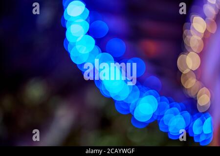 Blue bokeh light garland curving across a dark background with warm orange highlights, abstract Stock Photo
