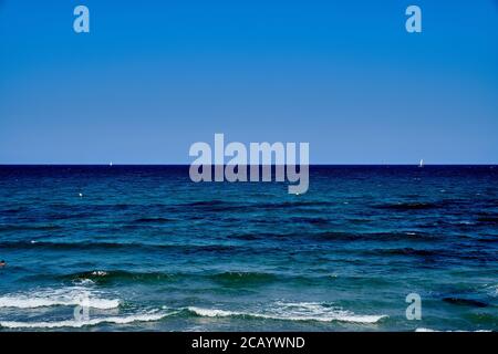 Deep blue Mediterranean Sea with white-capped waves under a clear sky, seen from San Juan beach, Alicante Stock Photo