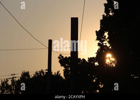 The sun sets - you see this from Palmovka, Prague. You can see a chimney in the distance. There is a contrail in the sky, from a passing aeroplane. Stock Photo