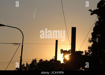 The sun sets - you see this from Palmovka, Prague. You can see a chimney in the distance. There is a contrail in the sky, from a passing aeroplane. Stock Photo