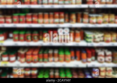 selves with canned vegetable food in supermarket, blurred refocused image Stock Photo