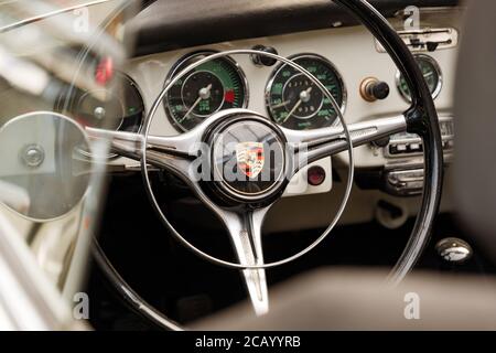 Selected focus at Porsche Logo on steering wheel inner classic and vintage Porsche sport car exhibit at Classic Remise in Düsseldorf, Germany. Stock Photo