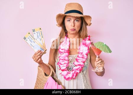 Middle age hispanic woman wearing hawaiian lei holding boarding pass and cocktail depressed and worry for distress, crying angry and afraid. sad expre Stock Photo