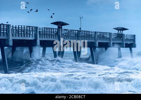 Large waves crash into the pier pilings at Jacksonville Beach as Tropical Storm Isaias passes by the Northeast Florida Coast. (USA) Stock Photo