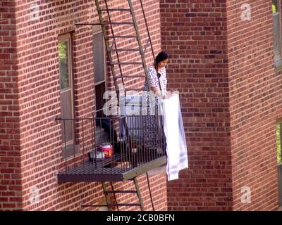 August 9, 2020, New York, New York, USA: Out the Window  Woman hangs clothes on the Fire Escape to dry during the Covid 19 pandemic  8/9/2020 (Credit Image: © Bruce Cotler/ZUMA Wire) Stock Photo