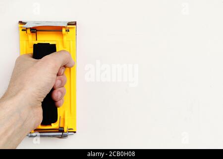 The yellow sandpaper holder in hand on white wall with copy space Stock Photo