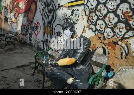 The statue of a man resting on a bench in the Old Town area of Phuket Town, Phuket, Thailand during  the Covid-19 outbreak equipped with a face mask Stock Photo