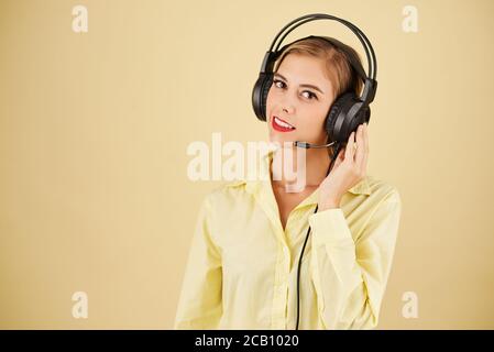 Portrait of technical support operator in headset having problems with connection, isolated on light yellow Stock Photo