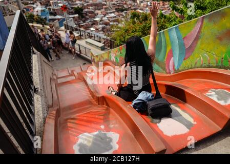 Medellin / Colombia - July 15, 2017: American tourist sliding down a slide in the Comuna 13 in Medellin Stock Photo