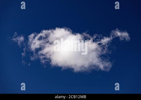 Small cumulus cloud in a deep blue sky Stock Photo