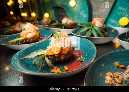 Freshly prepared salad lies inside the pineapple, which is cut lengthwise, sprinkled with grated cheese. Everything looks very appetizing. Stock Photo