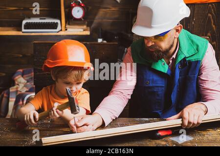 Father and son working with a hammer. Future kids profession. Construction of dad and boy in the garage. Stock Photo