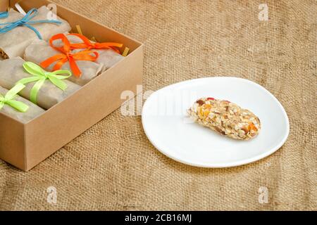 Bar of muesli on a saucer and boxes with bars. Sackcloth Stock Photo