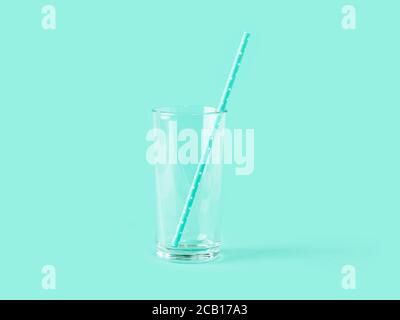 Empty tall transparent glass and paper drinking straw on mint green color background. Modern stylish tableware. Copy space. Front view. Stock Photo