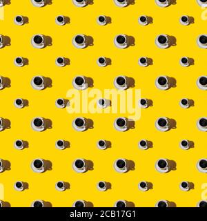 Seamless pattern of large and small cup of hot coffe on white saucer over a yellow background. Hot morning beverage minimal concept. Hard light shot. Stock Photo