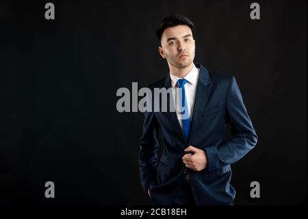 Portrait of business man wearing blue business suit and tie isolated on black background Stock Photo