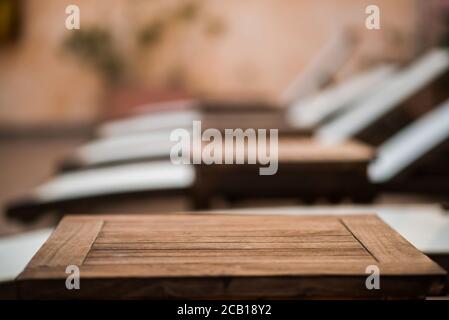 Top of Wooden Table. Blurred Background with Sunbeds. Using for Mock Up Template for Display of Your Design. Stock Photo