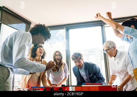 Business people having great time together.Colleagues playing table football in modern office. Stock Photo