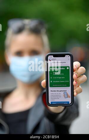 Woman with face mask shows smartphone with corona warning app, low risk, corona crisis, Baden-Wuerttemberg, Germany Stock Photo