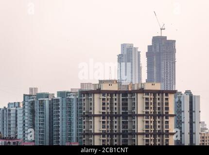 Mumbai, Maharashtra, India - March 2020: High rises under construction above the buildings of suburban Mumbai. Stock Photo