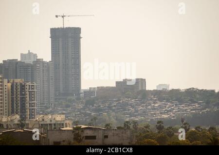 Mumbai, Maharashtra, India - March 2020: A view of the slums and a building under construction in the polluted haze of the city. Stock Photo