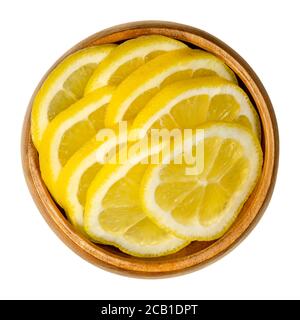 Fresh lemon slices in a wooden bowl. Sliced ​​ripe yellow citrus fruits. Citrus limon. Lemons are used for culinary purposes and for cleaning. Stock Photo