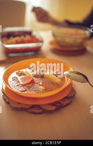 Soup with meatballs, potatoes and carrots in an orange plate on a wooden table Stock Photo