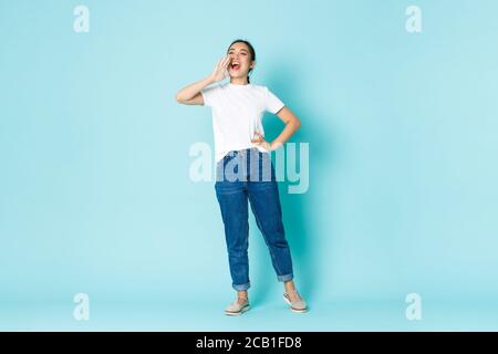 Fashion, beauty and lifestyle concept. Upbeat smiling, attractive asian girl calling for someone, making announcement, shouting loud as if searching Stock Photo