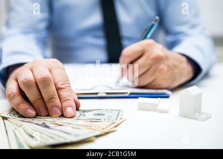Businessman with us dollars and symbolic houses and building projects, bodypart hands Stock Photo