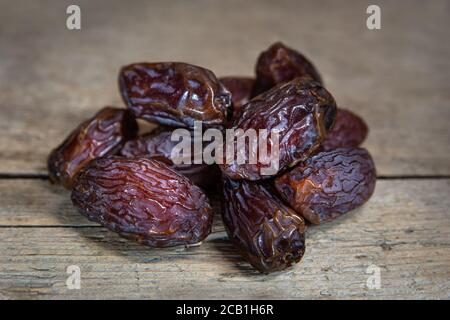 Dried dates on wooden table, sort chewy medjool, sweet vegan superfruit Stock Photo