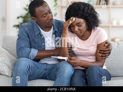 Closeup of upset black coouple having negative pregnancy test Stock Photo