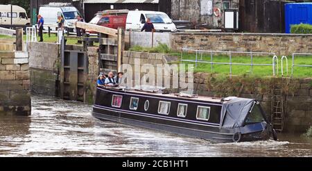 A black and purple canal narrow boat “Spirit of the bear” leaving Tarleton pushes against the incoming tide as it sets out to cross the Ribble Link. Stock Photo